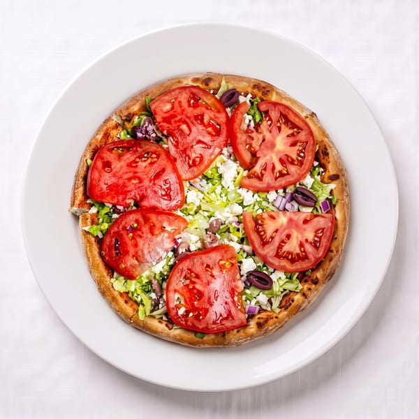 Overhead view of a small pizza topped with sliced tomatoes, lettuce, feta cheese, and olives.