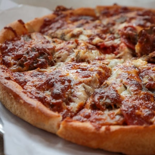 Close-up of a freshly baked, sliced pizza with melted cheese and rich red sauce.