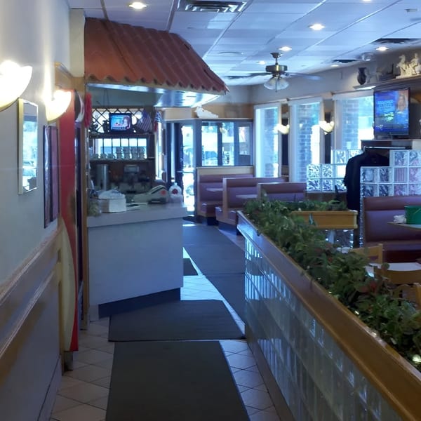 Interior view of a diner with booths, a counter, and a plant-filled divider.