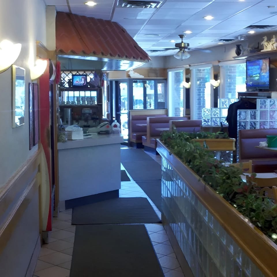 Interior view of a diner with booths, a counter, and a plant-filled divider.