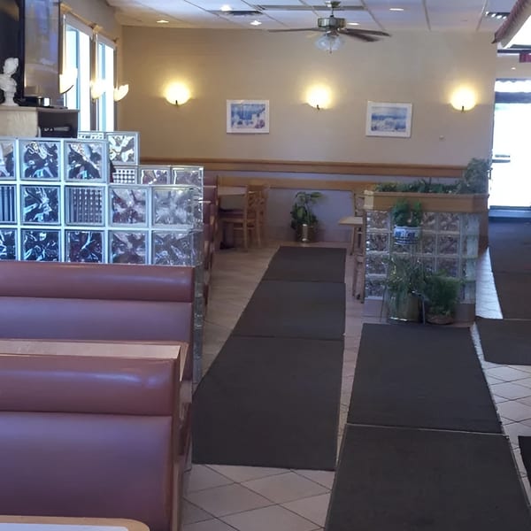 Interior of a restaurant with booths, tables, glass block dividers, and ceiling fans.