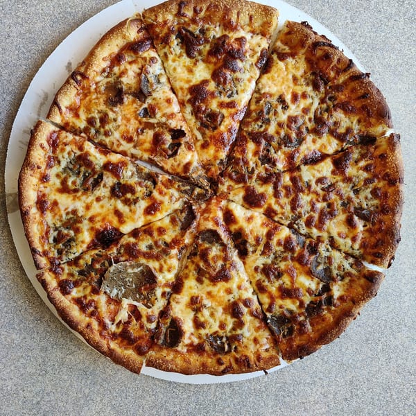A whole, sliced pizza with melted cheese and mushroom toppings on a white cardboard tray.
