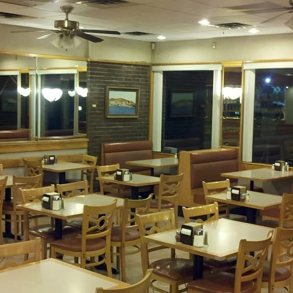 Interior of a diner with booths and tables, brick walls, and large windows.